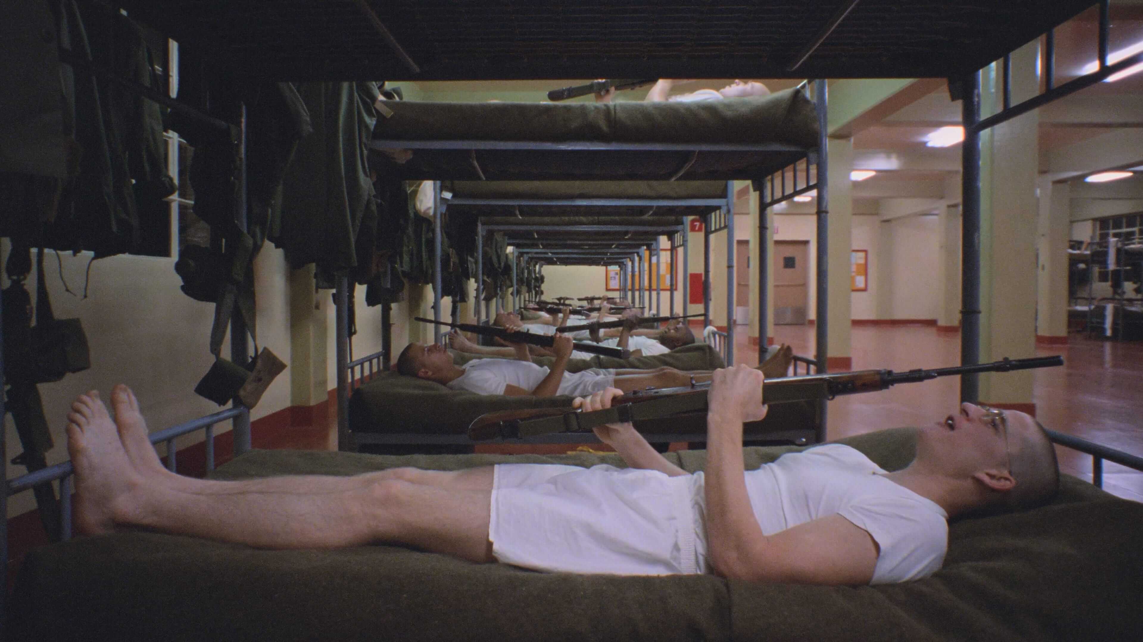 скриншот кадра с лежащими на кроватях солдатами с винтовками