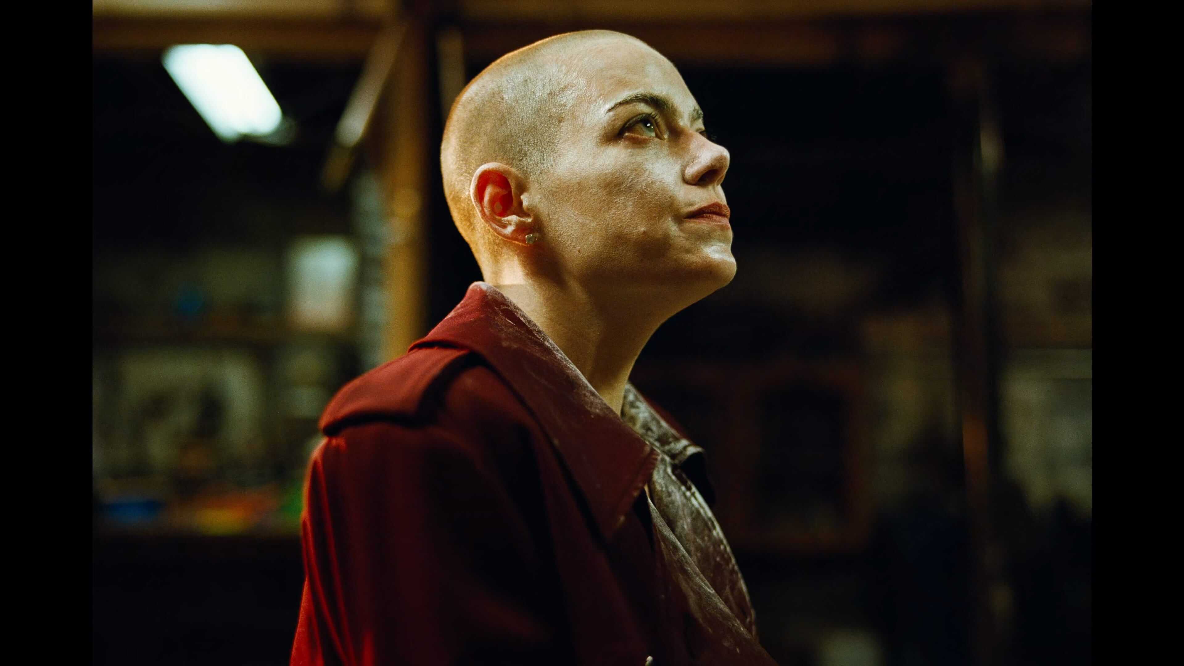 Портрет обритой наголо женщины в красном пальто