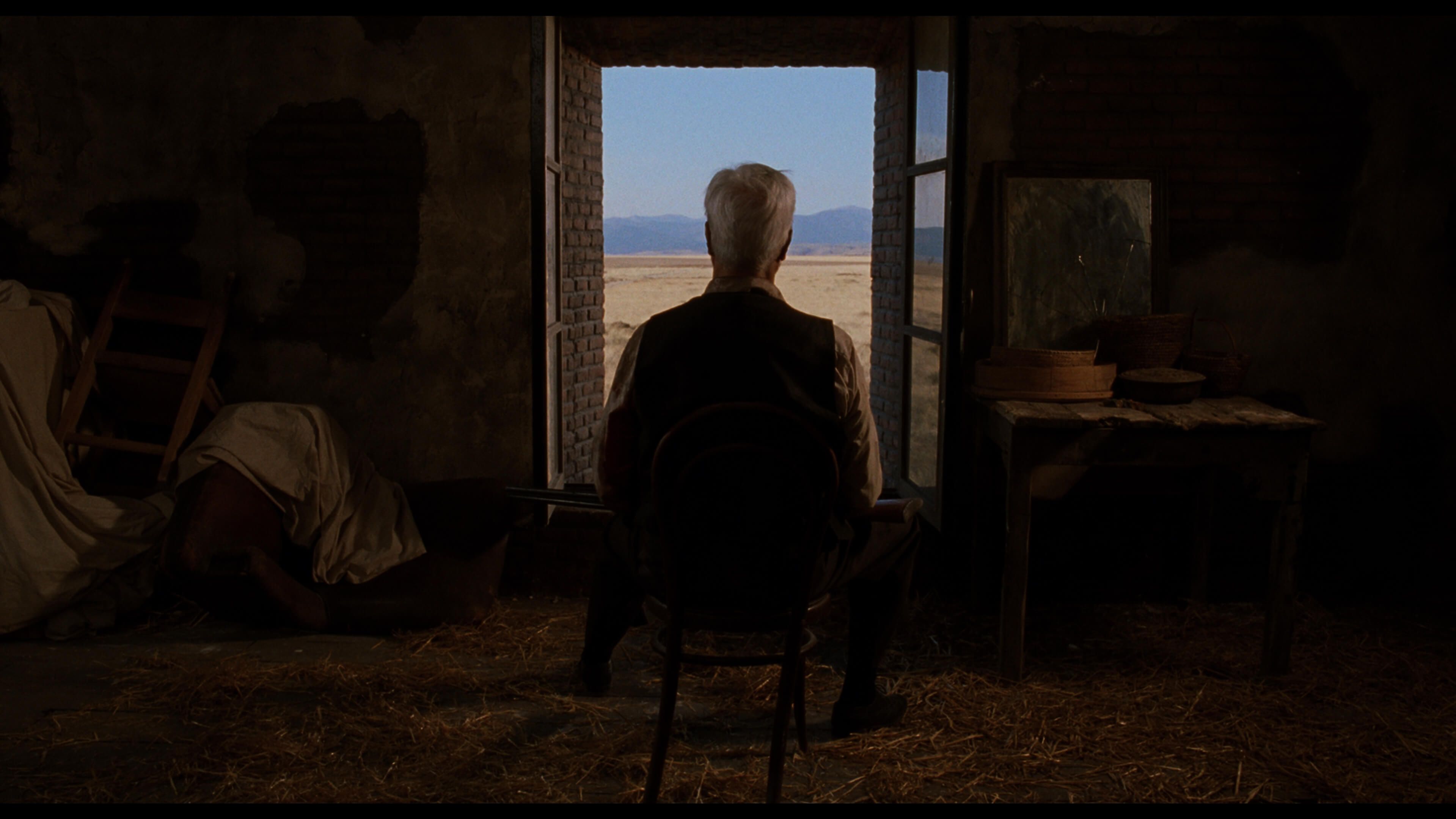 силуэт сидящего на стуле мужчины на фоне окна