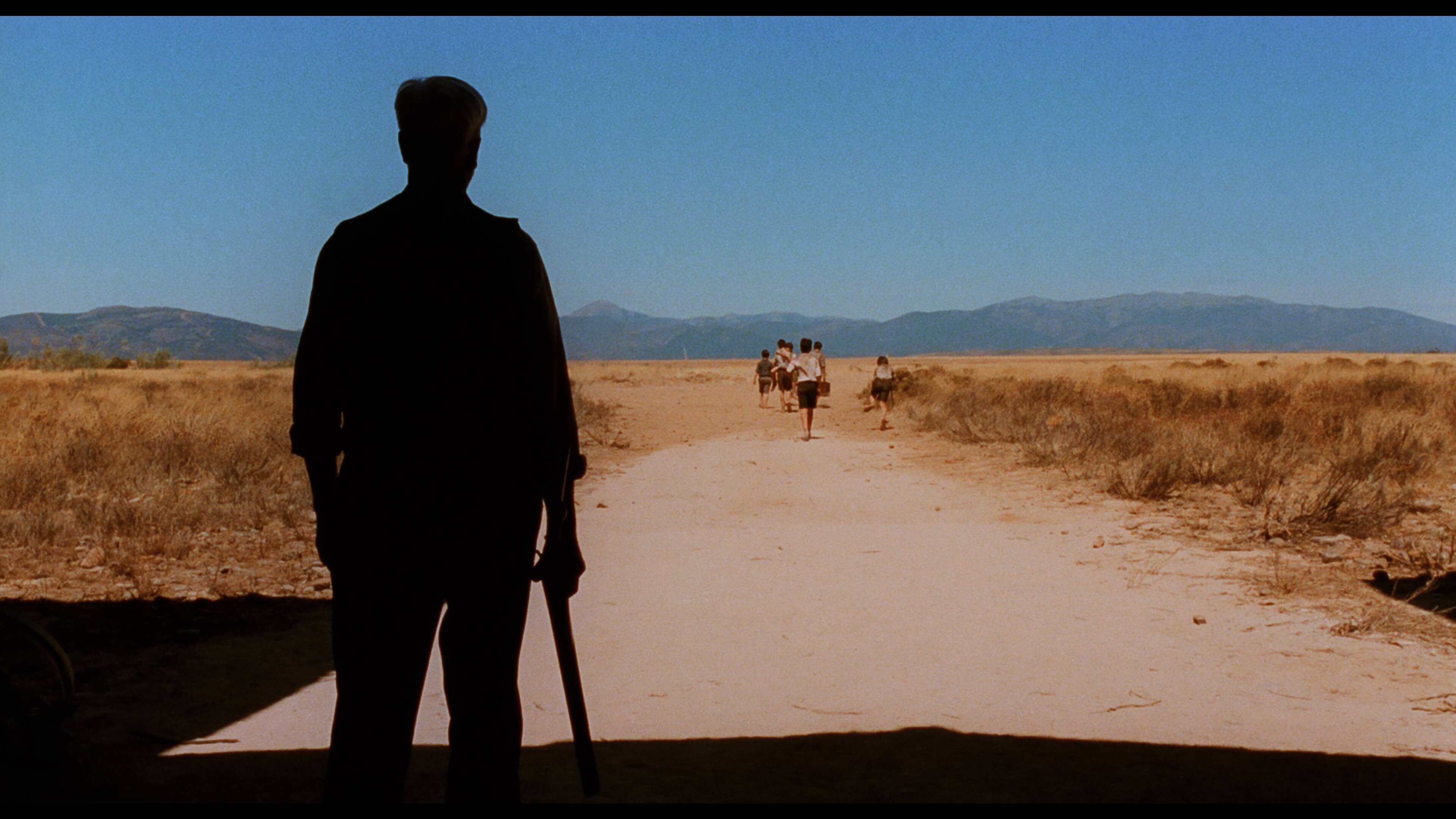 силуэт мужчина с ружьем, на фоне дети уходят в даль по дороге